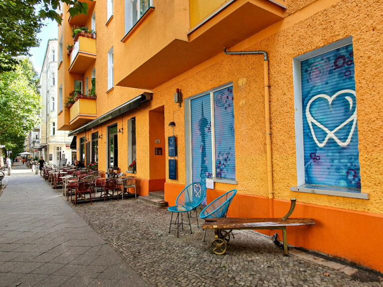 Ansicht von der Hufelandstr. 14 auf den Eingang der Praxis von Zahnarzt Ruben Hoeft, Lieblingszahnarzt.Berlin. Orange Hausfassade, Eingang im Erdgeschoss für Rollstuhl und Menschen mit Behinderung im Erdgeschoss.